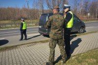 Policjant z ruchu drogowego i żołnierz WOT stoją przy drodze.