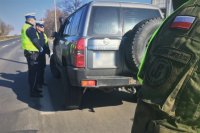 Policjant z ruchu drogowego i żołnierz WOT kontrolują pojazd.