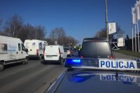 Dach policyjnego radiowozu, w tle pojazdy zatrzymywane do kontroli przez policjantów.