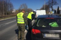 Policjant z ruchu drogowego i żołnierz WOT kontrolują pojazd.