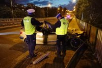 Policjanci z drogówki stoją przy wraku pojazdu uczestniczącym w zdarzeniu drogowym