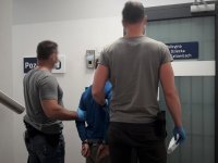 Nieumundurowani Policjanci trzymają zatrzymanego nieletniego
