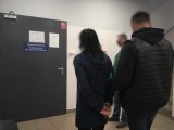 Policjanci nieumundurowani doprowadzają zatrzymaną kobietę