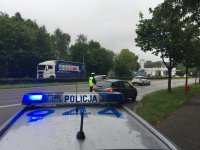 Na pierwszym planie dach policyjnego radiowozu, w tle policjanci kontrolują pojazd