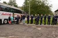 Policjanci stoją w kolejce do autobusu w którym oddaje się krew