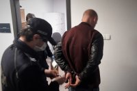 Umundurowani policjanci doprowadzają zatrzymanego