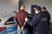 Umundurowani policjanci doprowadzają zatrzymanego
