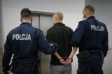 Umundurowani policjanci doprowadzają zatrzymanego.