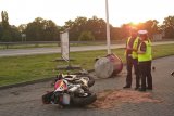 Dwaj policjanci stoją obok przewróconego motocykla.