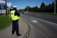 Policjant z drogówki mierzy prędkość nadjeżdżającego pojazdu.