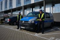 Policjanci z Wydziału Ruchu Drogowego KMP w Bielsku-Białej stoją obok oznakowanego radiowozu przed budynkiem komendy.