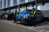 Policjanci z Wydziału Ruchu Drogowego KMP w Bielsku-Białej stoją obok oznakowanego radiowozu przed budynkiem komendy.