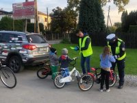 Policjanci rozdają odblaski pieszym i rowerzystom odblaski.