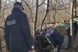 Policjanci zaglądają do prowizorycznego szałasu.