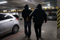 Policjant nieumundurowany prowadzi zatrzymanego przez parking podziemny