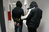 Policjant nieumundurowany stoi z zatrzymanym na korytarzu komendy