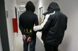 Policjant nieumundurowany stoi z zatrzymanym na korytarzu komendy