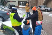 Policjantka ruchu drogowego zakłada pieszemu opaskę odblaskową na rękę.