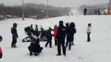 Policjanci stoją obok służbowego quada, na którym siedzą dzieci. Zdjęcie wykonane na zboczu stoku narciarskiego.