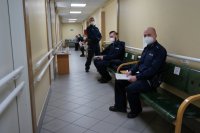 Policjanci siedzą kolejce do szczepienia na koronawirusa.
