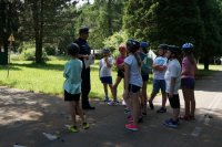 Policjant ruchu drogowego rozmawia z dziećmi. Zdjęcie zrobione na ścieżce edukacyjnej w miasteczku rowerowym.