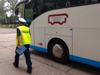 Policjant z ruchu drogowego idzie wzdłuż autokaru