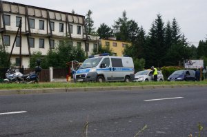 Zdjęci z oddali, na którym widać policyjny motocykl i busa oraz policjantów kontrolujących dwa pojazdy.