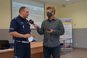 Dziennikarz radiowy prowadzi wywiad z policjantem ruchu drogowego.