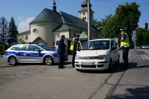 Policjanci z drogówki prowadzą akcję profilaktyczną na drodze, z uczestnikami ruchu drogowego.