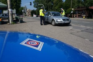 Policjanci z drogówki prowadzą akcję profilaktyczną na drodze, z uczestnikami ruchu drogowego.