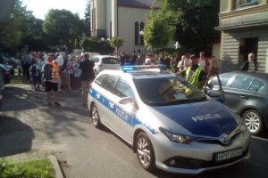 Policyjny radiowóz stoi przed piesza pielgrzymką