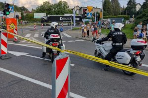Policjanci na motocyklach obserwują drogę na trasie wyścigu