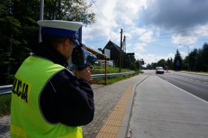 Policjant z ruchu drogowego mierzy prędkość ręcznym radarem.