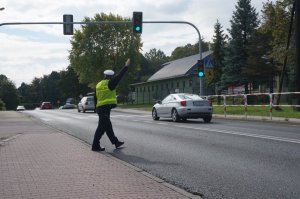 Policjant z ruchu drogowego daje znaki nakazujące kierowcy zjechanie z drogi