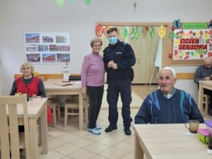 Policjant dzielnicowy rozmawia z seniorami podczas spotkania na świetlicy.