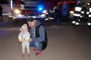 Mężczyzna kuca z małym dzieckiem. Zdjęcie wykonane w nocy.