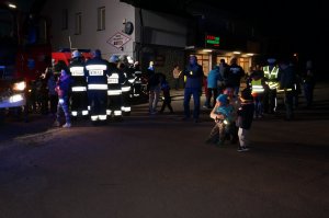 Uczestnicy akcji profilaktycznej, na zdjęciu strażacy i cywile. Zdjęcie wykonane w nocy.