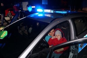 Kobieta siedzi z dzieckiem na miejscu kierowcy w radiowozie policyjnym.