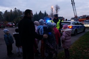 Policjantka z ruchu drogowego rozdaje uczestnikom akcji profilaktycznej opaski odblaskowe.