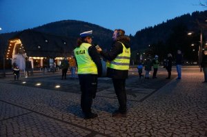 Policjantka udziela wywiadu radiowego, w tle góry. Zdjęcie wykonane o zmierzchu.