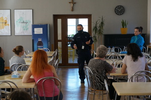 Policjant w stołówce pensjonatu prowadzi prelekcję z kobietami z Ukrainy.