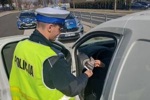 Policjant wręcza ulotkę kierowcy