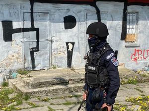 Policjant w kamizelce taktycznej i hełmie ochronnym stoi na tle grafitti