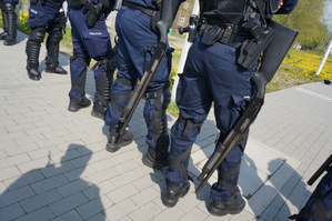 Zbliżenie na policyjne strzelby podwieszone przy bokach policjantów