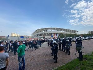 Kibice wchodzą na stadion, obok oddział policjantów prewencji