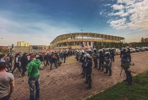 Kibice wchodzą na stadion piłkarski, obok policjanci z oddziału prewencji