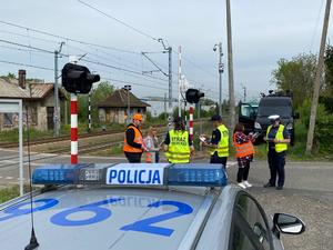 Policjanci, pracownicy kolei i Straży Ochrony Kolei rozmawiają z kierowcami w rejonie przejazdu kolejowego.