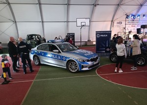 Policyjne bmw, obok policjanci rozmawiają z ludźmi.