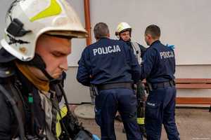 Zbliżenie na strażaka pożarnego. Na drugim planie rozmawiają policjanci