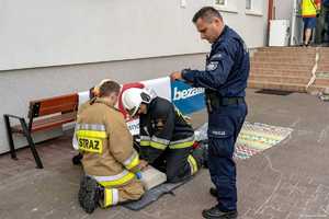 Strażacy ćwiczą reanimację na manekinie, obok stoi policjant.